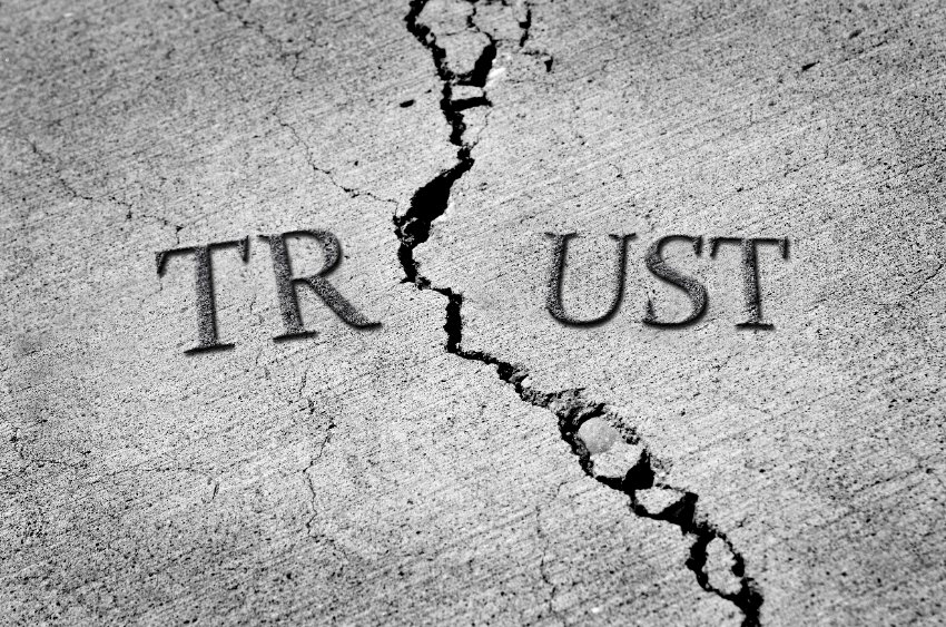Word "Trust" inscribed in concrete, broken by a crack