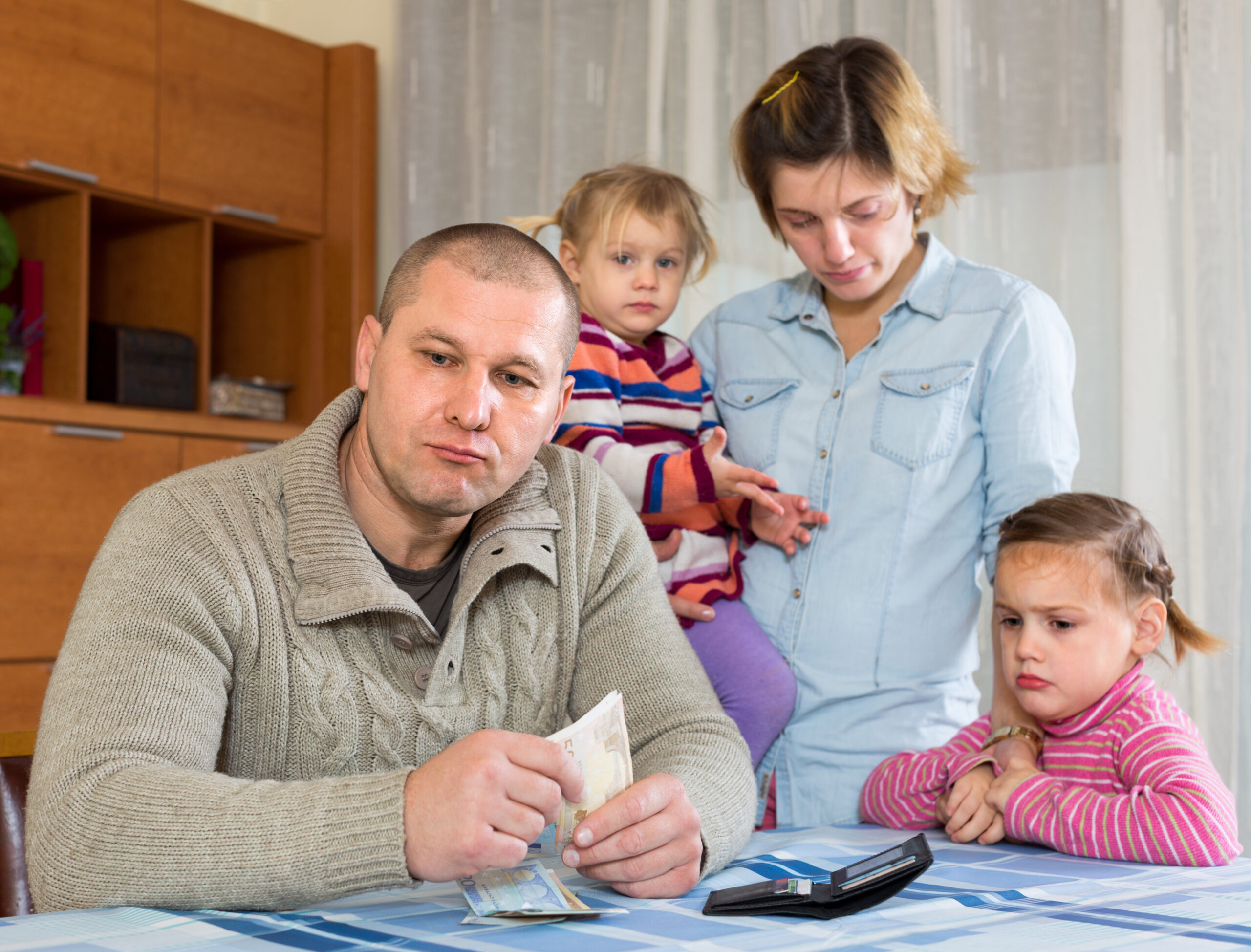 Couple with two small children looking stressed over money